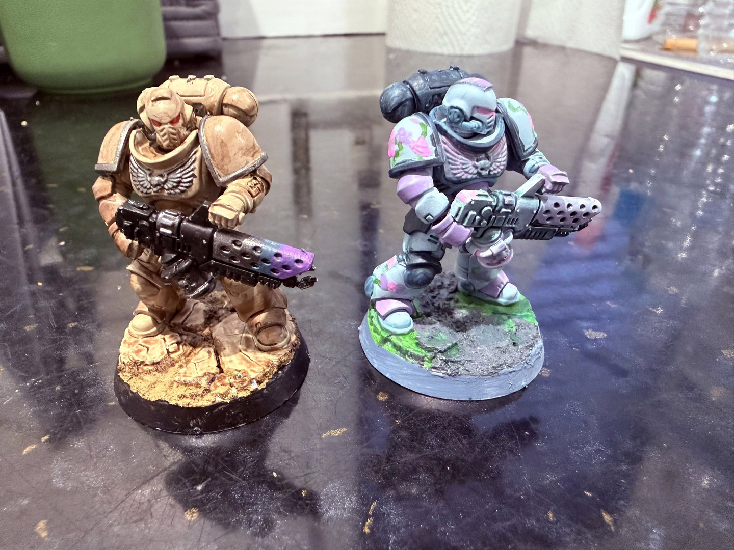 Front view of 2 painted Space Marine miniatures, one in tan and one with a flowery baby blue pattern