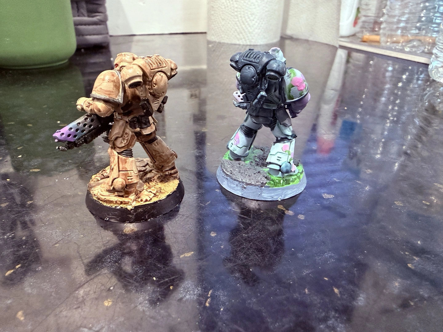 Rear view of 2 painted Space Marine miniatures, one in tan and one with a flowery baby blue pattern